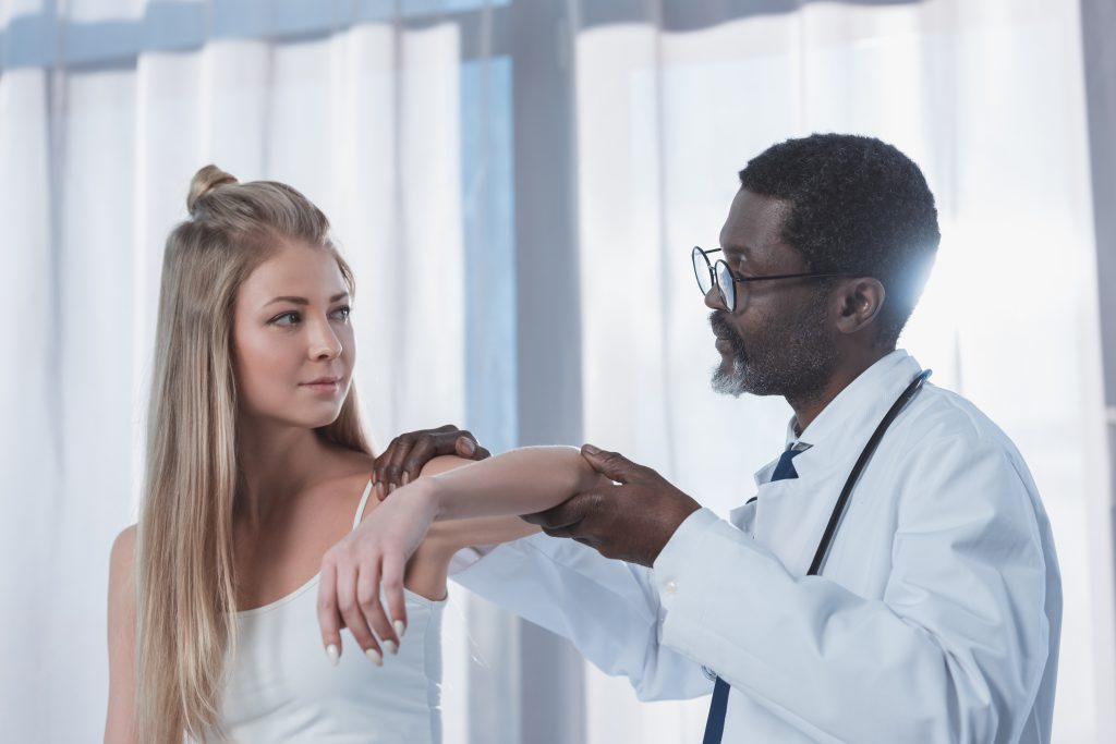 african american Doctor examining patient injured elbow