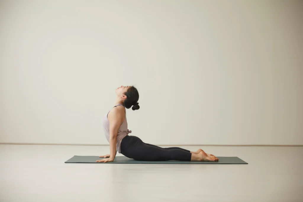 Woman performing an upward-facing dog yoga pose on a mat, representing effective exercises for strengthening the cervical spine.